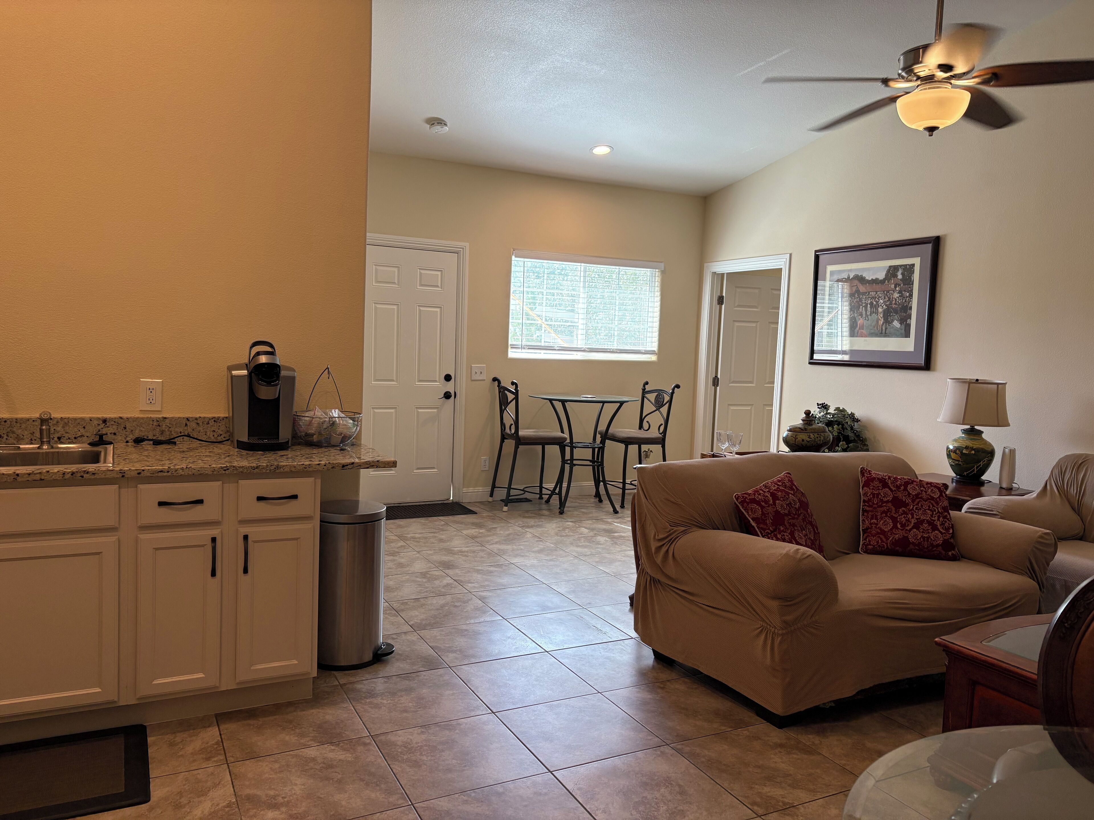 Un espacio habitable compacto con kitchenette, comedor y zona de estar con sofá.