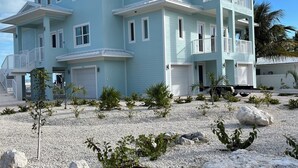 A two-story building with multiple balconies and a covered driveway. - NEW - Luxury Waterfront Island Home - BEACH, Pool & Dock (Marathon)