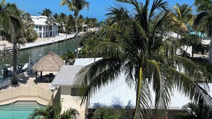 Een resort met een zwembad, palmbomen en een helderblauwe lucht.