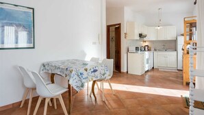 Eine moderne Küche mit weißen Schränken und einem Essbereich mit Tisch und Stühlen.