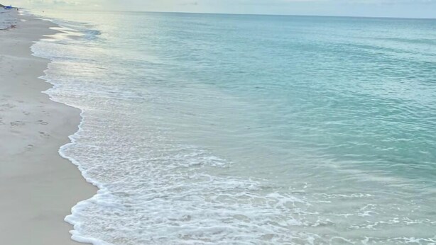 Una spiaggia con acque cristalline turchesi e onde calme.