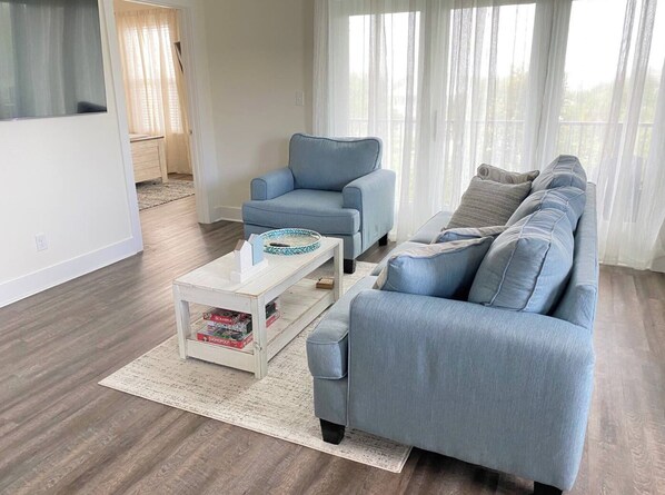 Un salon moderne avec un canapé gris, une table basse blanche et un fauteuil gris.