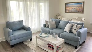 Un soggiorno con un divano blu chiaro, una poltrona abbinata, un tavolino da caffè con libri e un quadro appeso al muro.