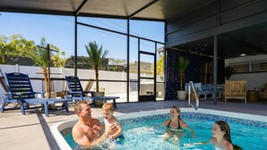 Un espace piscine avec une eau d’un bleu limpide, des chaises longues et un coin salon abrité.