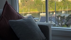 Quarto com sofá e uma grande janela com vista para uma marina e edifícios.