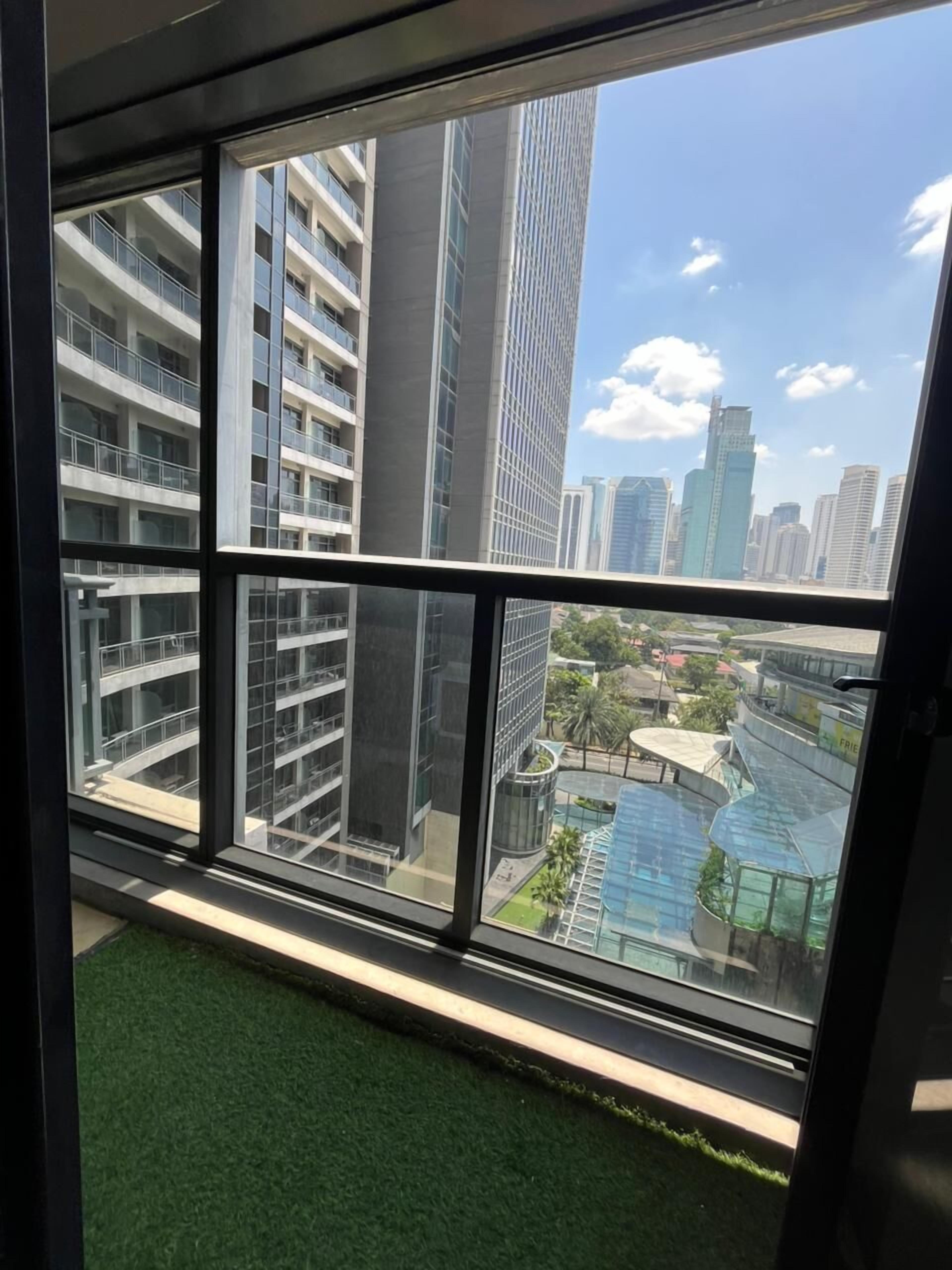 A view through a window with a view of high-rise buildings and a swimming pool.