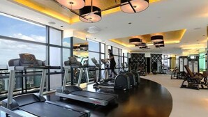 Une salle de sport moderne équipée de tapis de course, de vélos elliptiques et de matériel de musculation.