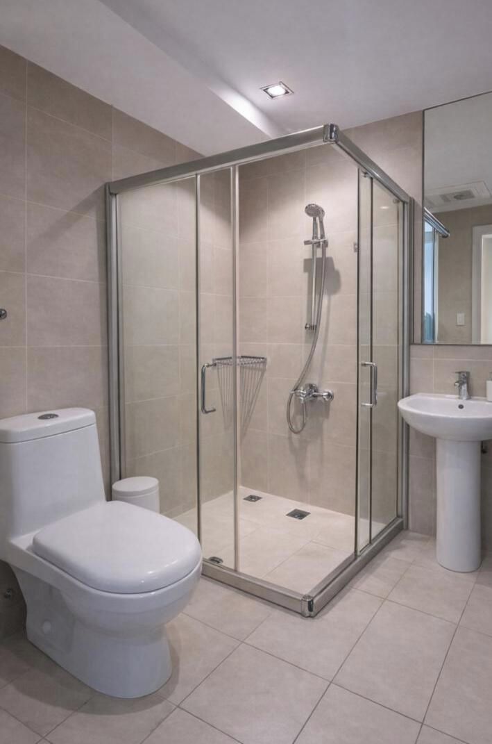 Un baño moderno con ducha de vidrio, inodoro y lavamanos.