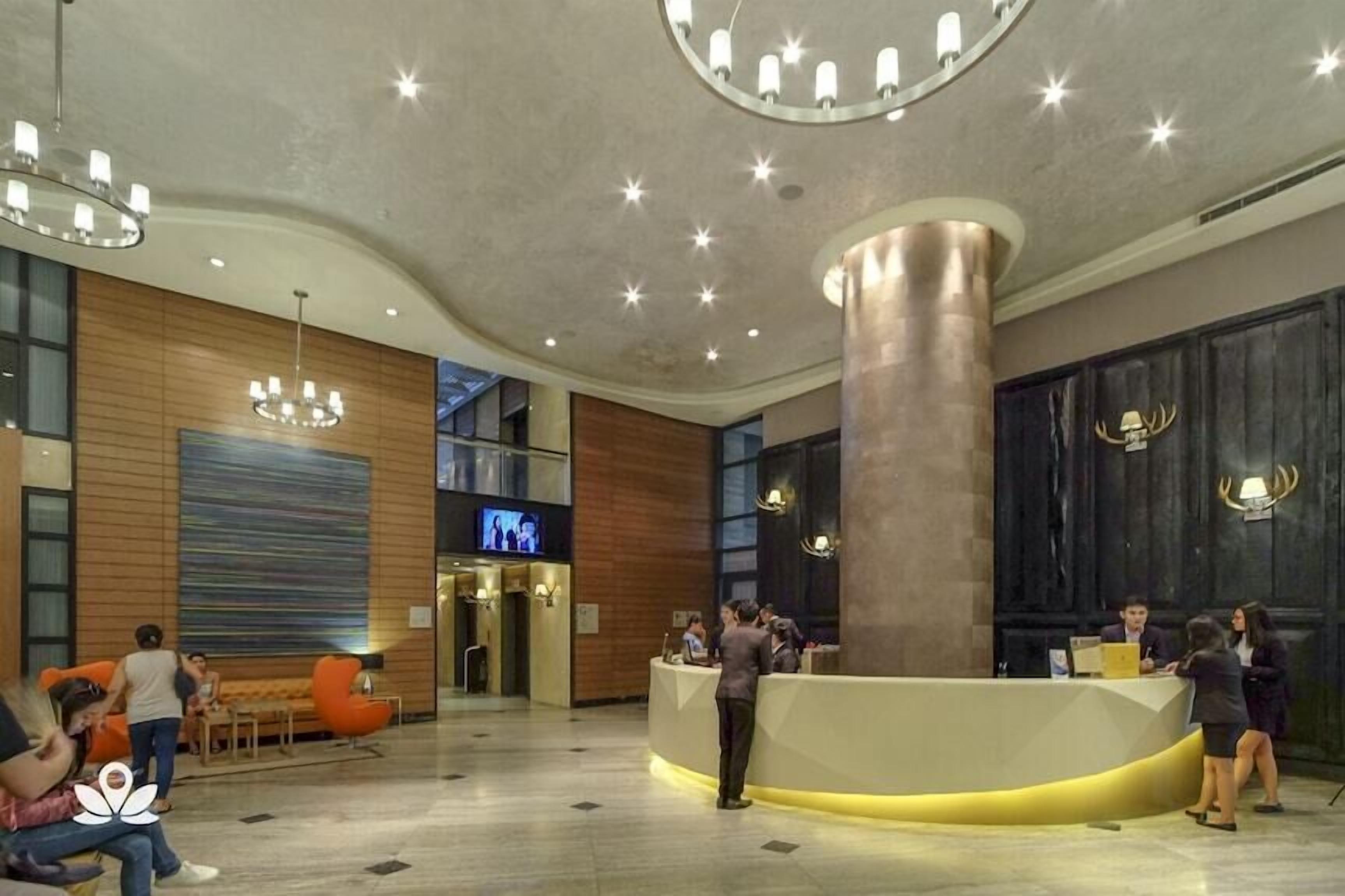 En modern hotellobby med en receptionsdisk, en sittgrupp och en stor pelare.