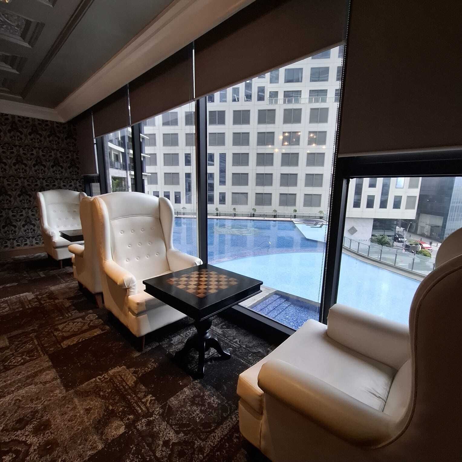 A hotel room with a large window, a pool view, and a chess table.