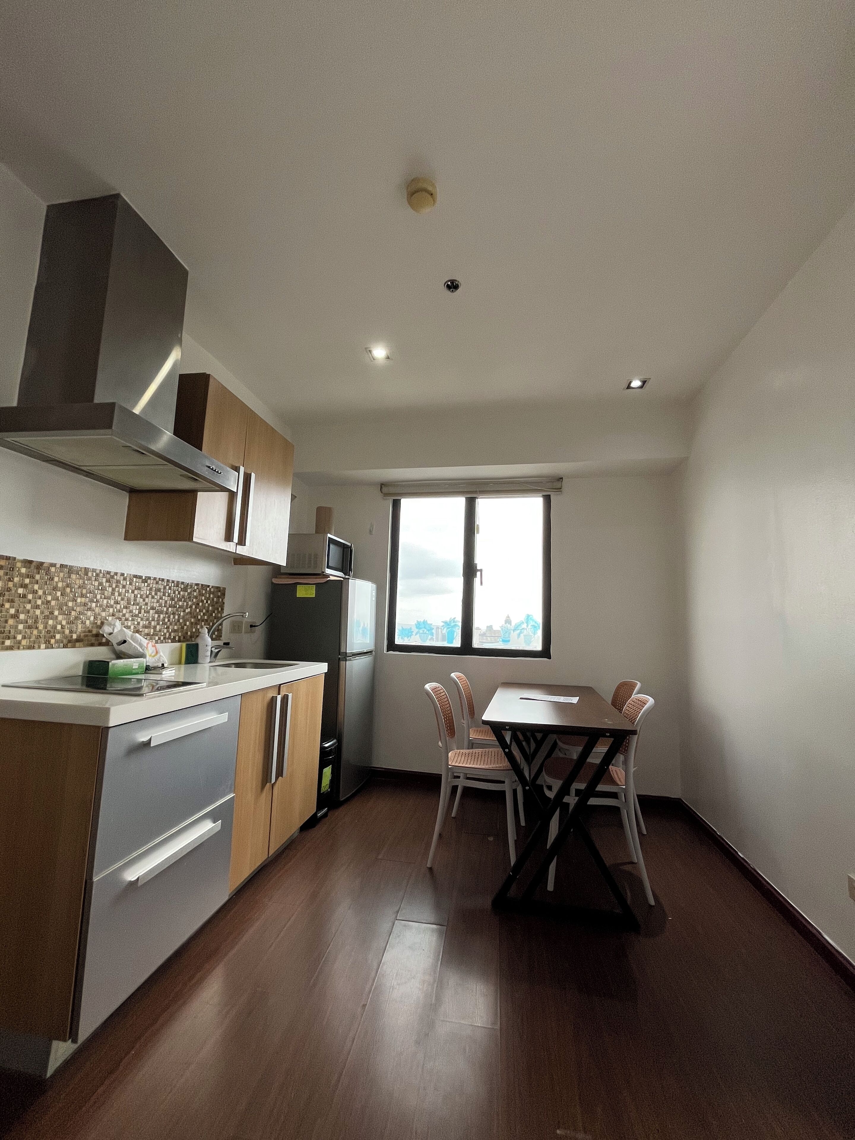 A modern kitchen with wooden cabinets, a built-in stove, and a dining area with a table and chairs.