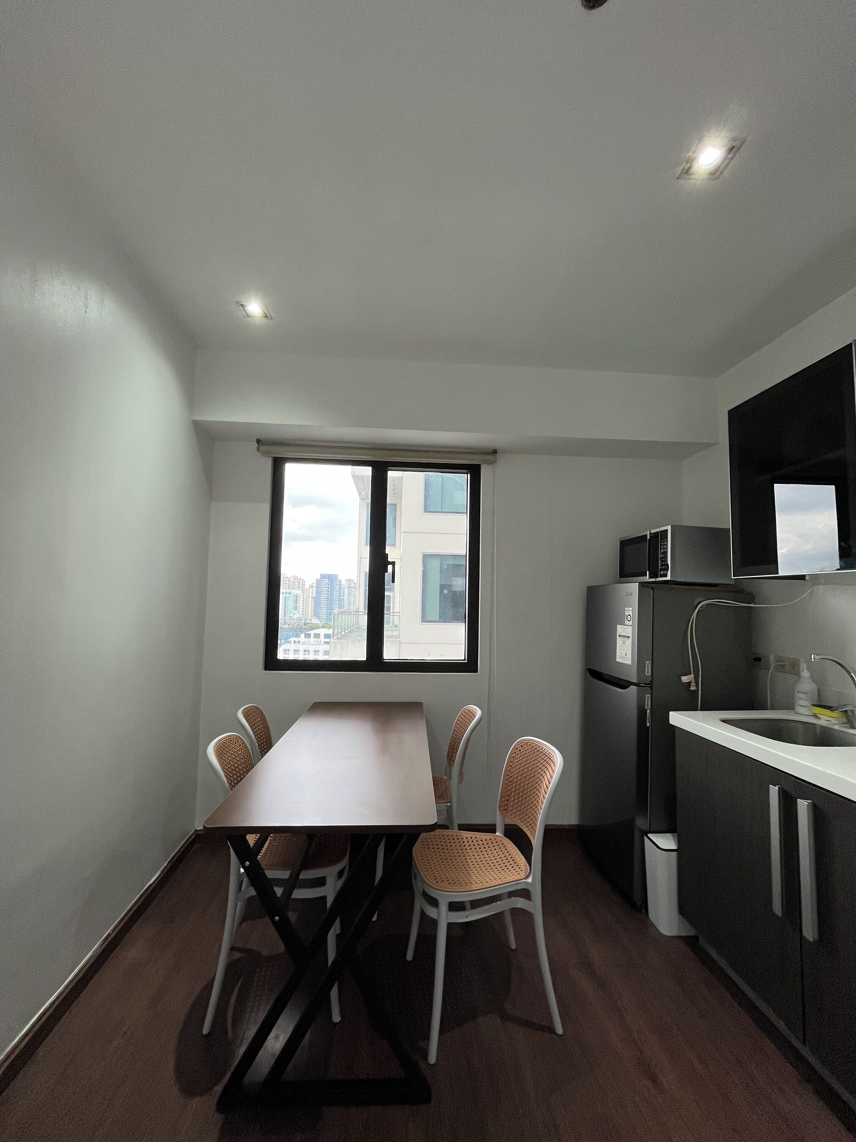 Una cucina compatta con angolo ristoro, frigorifero e finestra vista città.