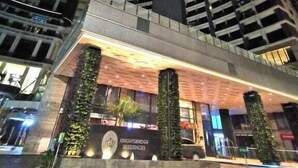 Un moderno edificio de gran altura con fachada curva, iluminado por luces verticales.