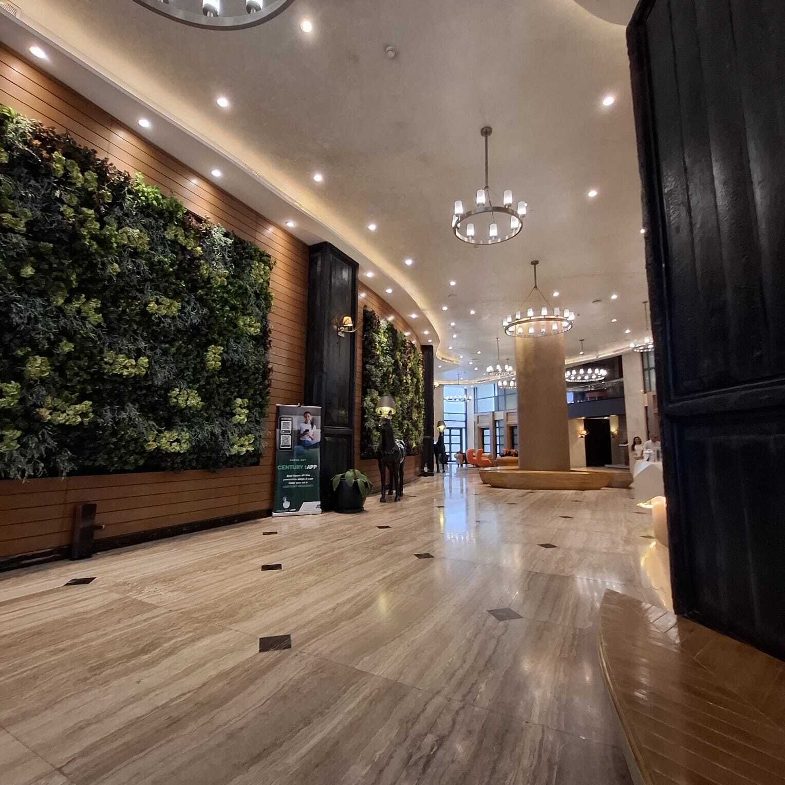A spacious lobby with a green vertical garden wall, polished marble flooring, and modern lighting fixtures.