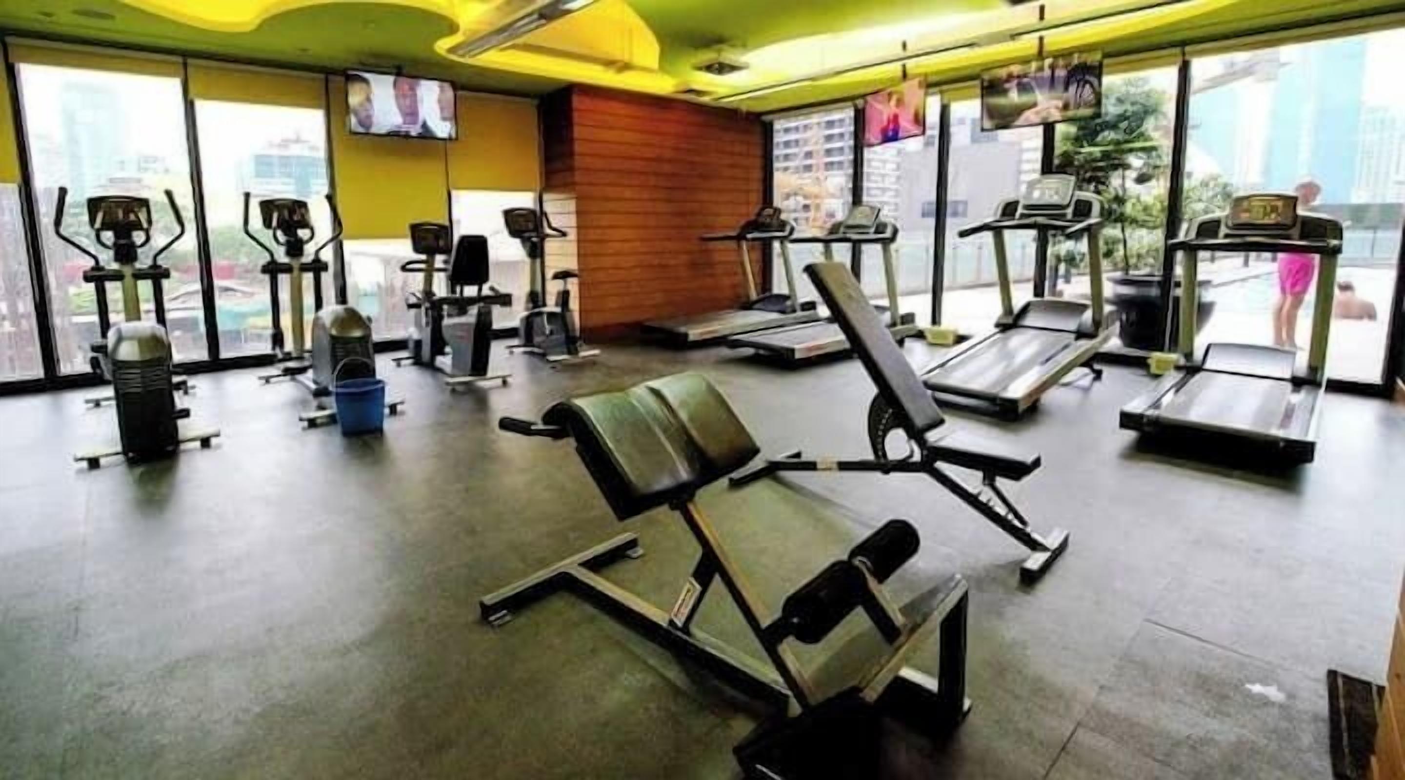 Una palestra con diverse attrezzature per l'allenamento, tra cui tapis roulant, cyclette e macchinari per pesi.