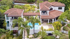 A large, multi-story house with a swimming pool surrounded by lush greenery. - Stunning Vacation Villa Rental in the British Virgin Islands (Mahoe Bay)