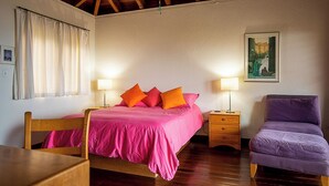 A bedroom with a wooden bed, two bedside tables, a chair, and a painting on the wall. - Stunning Vacation Villa Rental in the British Virgin Islands (Mahoe Bay)