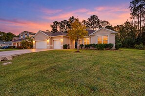 A two-story house with a front yard and a driveway. - Dog-friendly Home With Tesla EV Charger, Yard, Patio, Grill, AC, & W/D (Palm Coast)