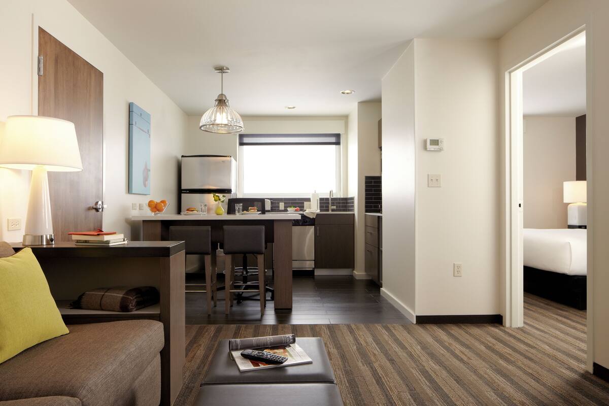 Habitación de hotel con sala de estar, kitchenette y dormitorio separado.