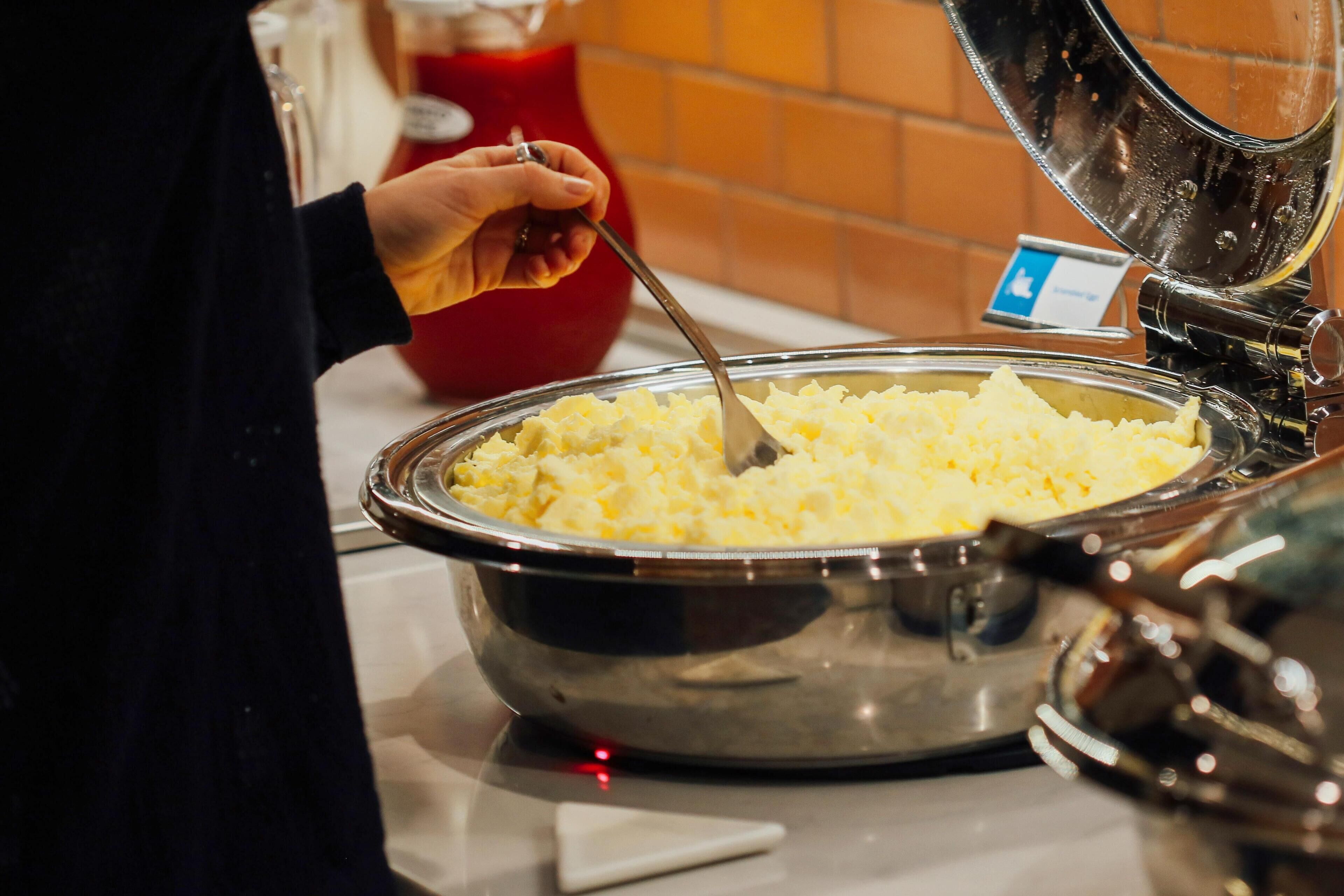 A buffet setup with a large metal bowl of mashed potatoes.