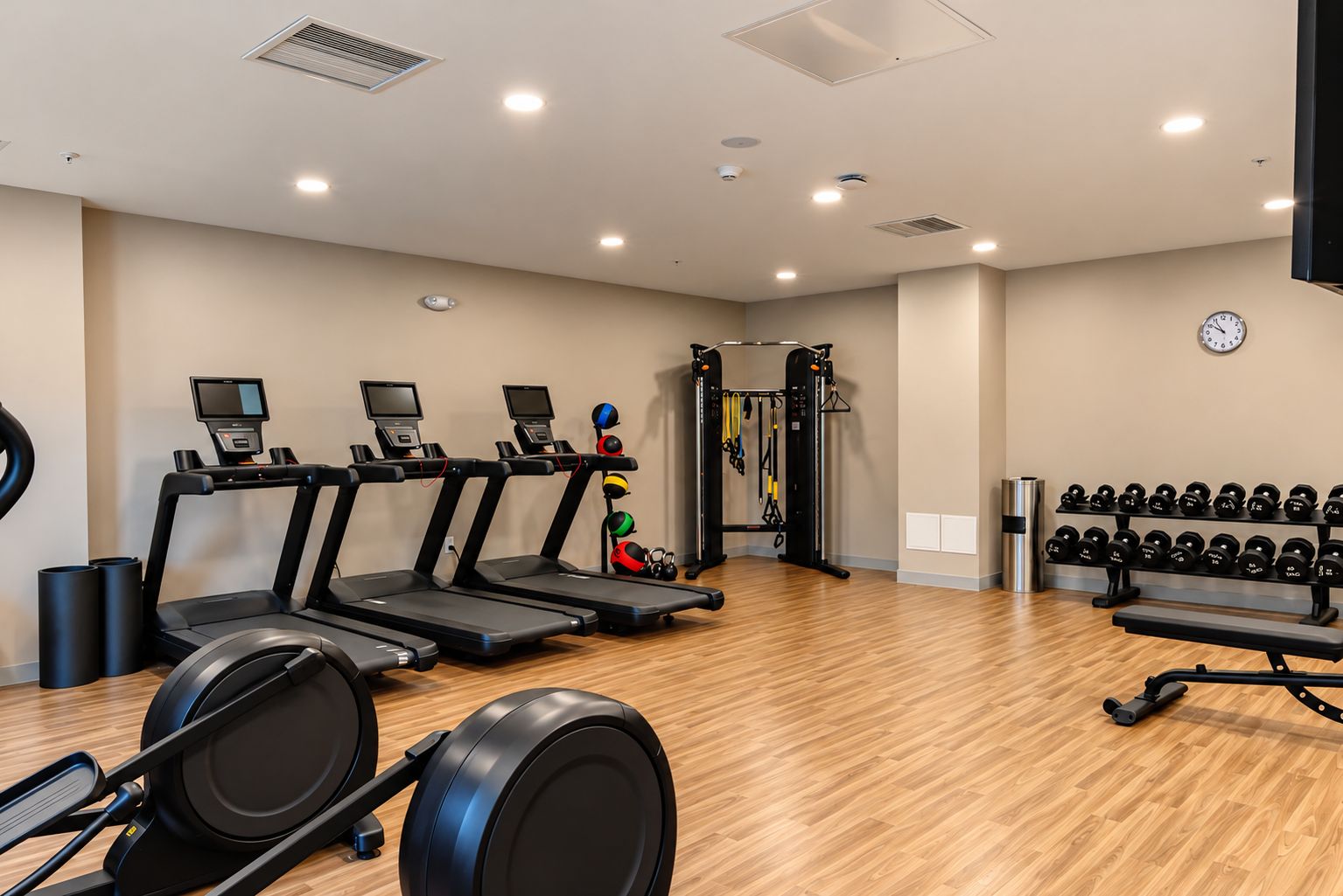 Une salle de sport équipée de tapis de course, d’un banc de musculation et d’un support pour les exercices de squat.