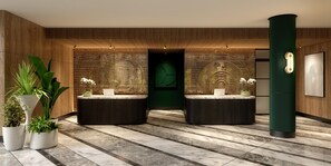 Un espace d’accueil comprenant deux comptoirs de réception, des plantes en pot, un mur végétal orné d’un motif circulaire et une haute colonne verte.