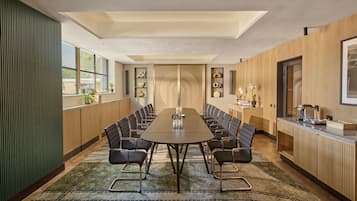 A conference room with a long table, chairs, and a wooden accent wall.