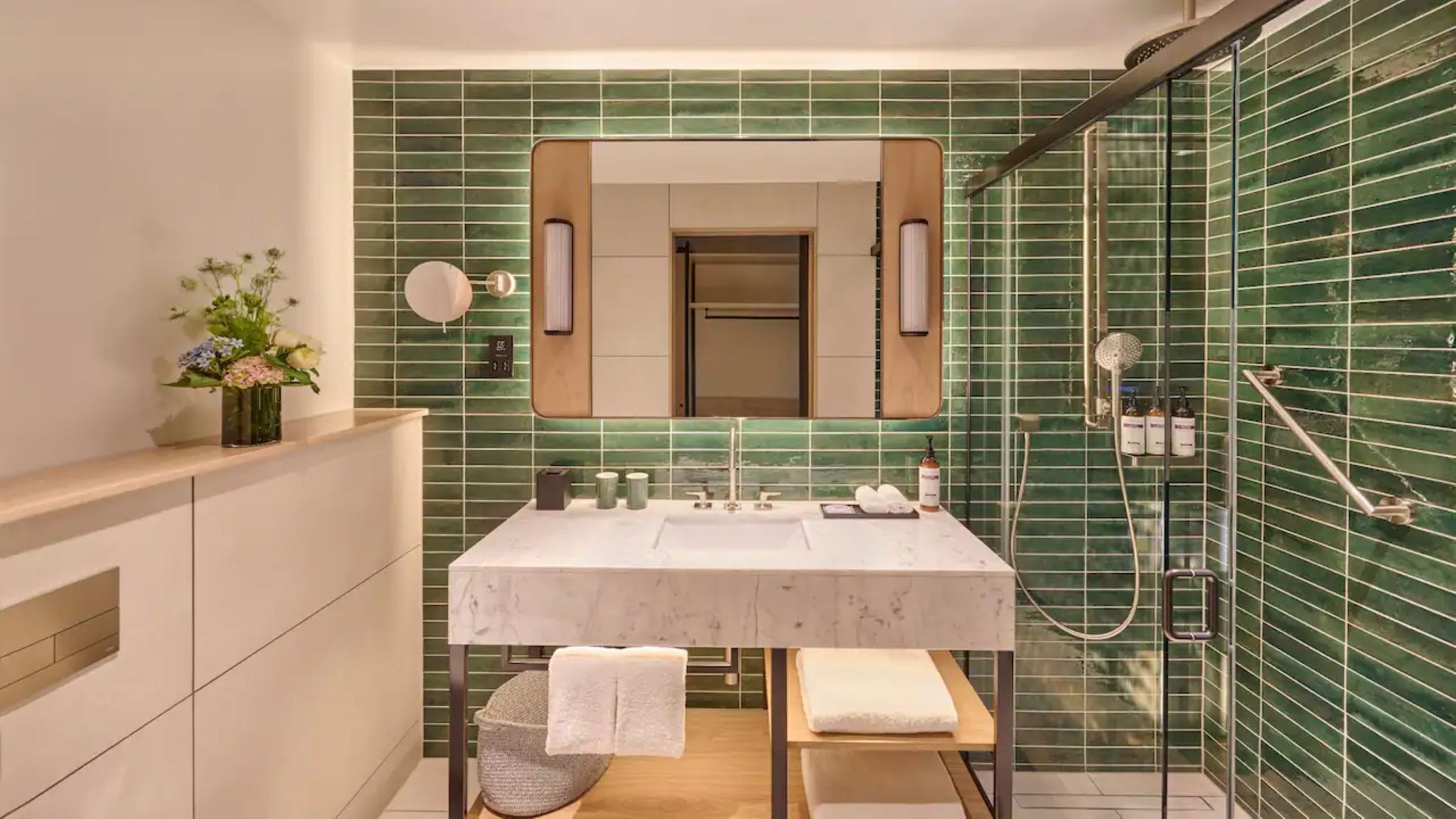 A modern bathroom with a marble sink, a large mirror, and a shower enclosure.