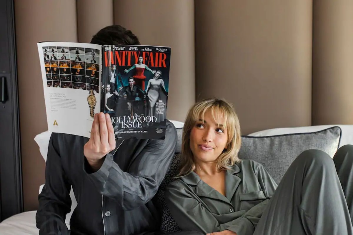 Una persona sentada en una cama leyendo una revista.