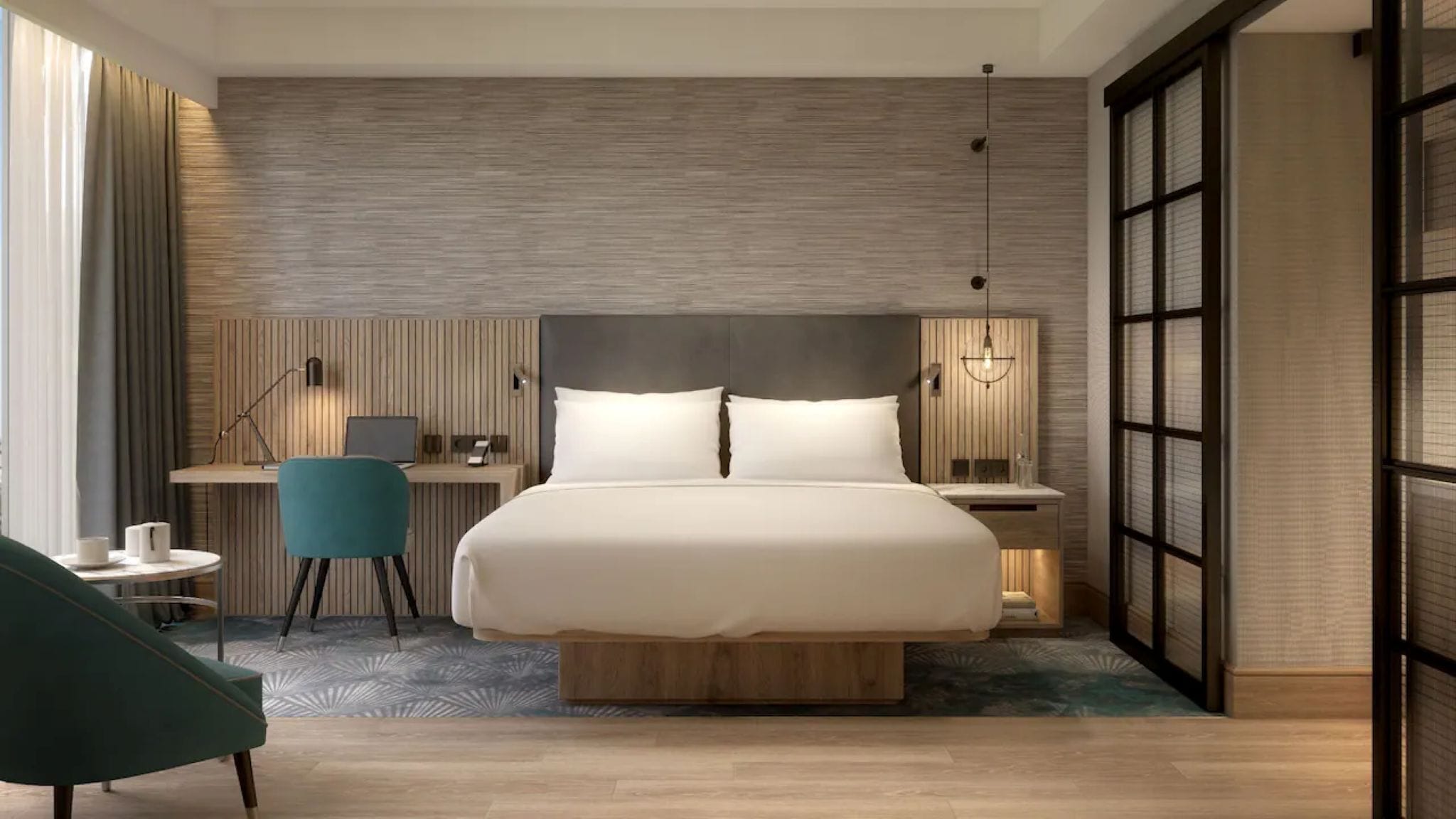 A modern hotel room with a large bed, a desk, a chair, and a walk-in closet.