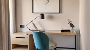 A modern workspace with a desk, chair, and a framed abstract artwork. - Hyatt Regency London Olympia (London)