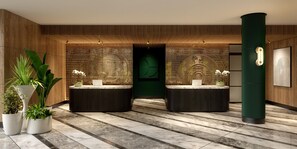 A reception area with two reception desks, potted plants, a green wall with a circular design, and a tall green column. - Hyatt Regency London Olympia (London)