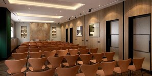Une salle de conférence avec des rangées de chaises, un mur en bois orné de tableaux encadrés et un plafond au design moderne.