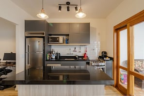 A modern kitchen with a central island, stainless steel appliances, and pendant lighting. - Casa Pet Friendly no Condom nio Bell Park (São José dos Campos)
