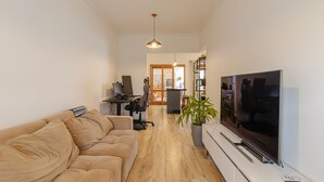 A modern living room with a sofa, TV, and a desk with a computer. - Casa Pet Friendly no Condom nio Bell Park (São José dos Campos)