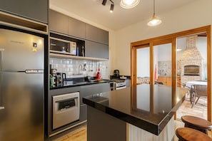 A modern kitchen with stainless steel appliances, a central island, and a built-in oven. - Casa Pet Friendly no Condom nio Bell Park (São José dos Campos)