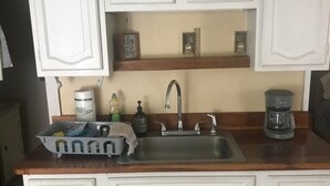 A kitchen with white cabinetry, a double sink, and a coffee maker.