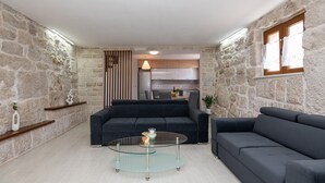 Ein modernes Wohnzimmer mit einer Couch, einem Glastisch und einer Küche im Hintergrund.