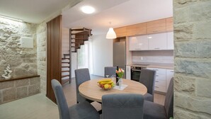 Eine moderne Küche mit weißen Schränken, einer Holztreppe und einem Essbereich mit grauen Stühlen und einem runden Tisch.