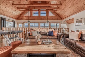 A spacious living room with a high wooden ceiling, large windows, a fireplace, and a billiards table. - Splash Pool-Game Room & Xbox-Hot Tub-Prime Location (Sevierville)