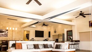 A spacious living room with a large sectional sofa, a coffee table, and a kitchen area visible through an open archway. - Ocean View Penthouse in the Main Center (Playa del Carmen)