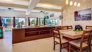 A spacious kitchen with a large island, wooden chairs, and a dining table. - Ocean View Penthouse in the Main Center (Playa del Carmen)