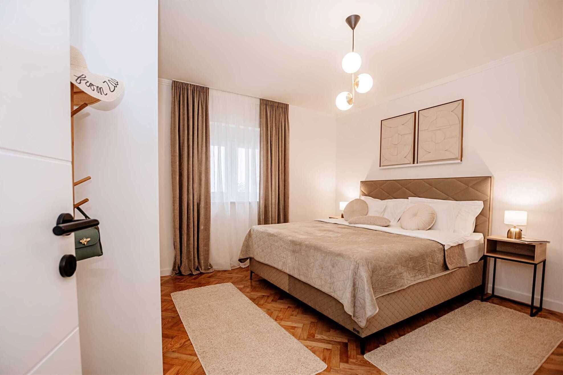 Una habitación de hotel con una cama, una mesita de noche, una lámpara, una luz en el techo y una puerta con perchero para toallas.