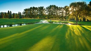 A golf course with a pond, trees, and a clear sky. - Rustic 2BR Cabin at Christmas Mountain Village – Family Adventure Awaits (Wisconsin Dells)