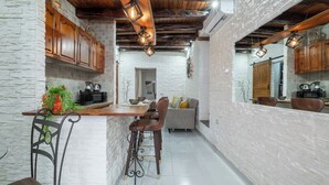 A kitchen with white brick walls, wooden cabinets, and a central island with bar stools. - Su Lizu, charm and relaxation in the historic center of Cagliari - with patio. (Cagliari)