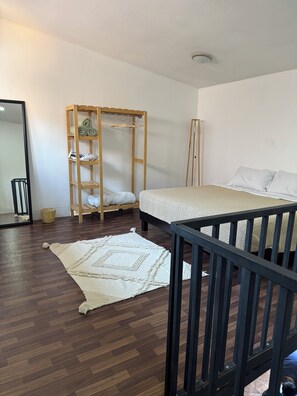 A bedroom with a wooden wardrobe, a bed with white bedding, a wooden floor, and a mirror. - Minimalist Loft 3 Blocks from the Zócalo (Oaxaca de Juárez)