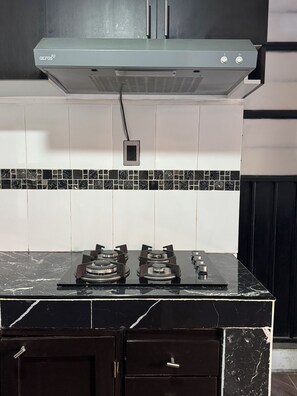 A kitchen with a gas stove, a range hood, and a tiled backsplash. - Minimalist Loft 3 Blocks from the Zócalo (Oaxaca de Juárez)