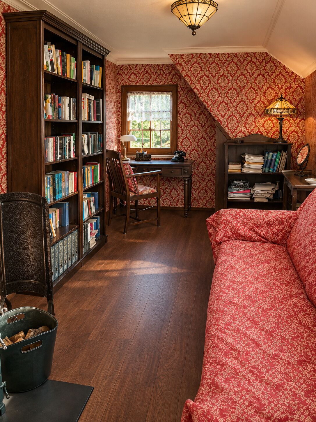 Une pièce chaleureuse avec un bureau en bois, des étagères à livres, un canapé rouge à motifs et une fenêtre donnant sur un beau paysage.