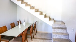 Un comedor con una mesa larga, sillas y una escalera de diseño único.