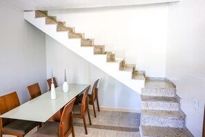 Ein Essbereich mit einem langen Tisch, Stühlen und einer Treppe mit einem besonderen Design.